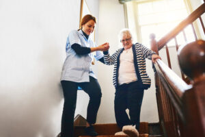 Caregiver helping senior woman walking down stairs