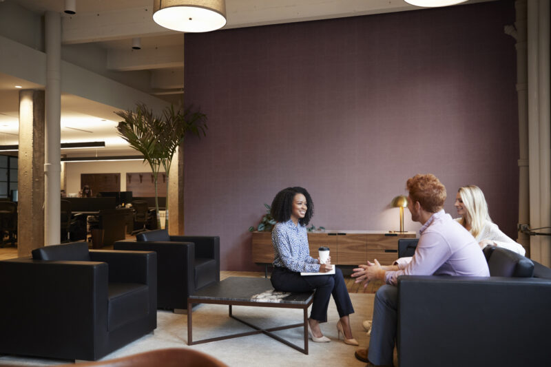 Three colleagues at a casual work meeting in a lounge area